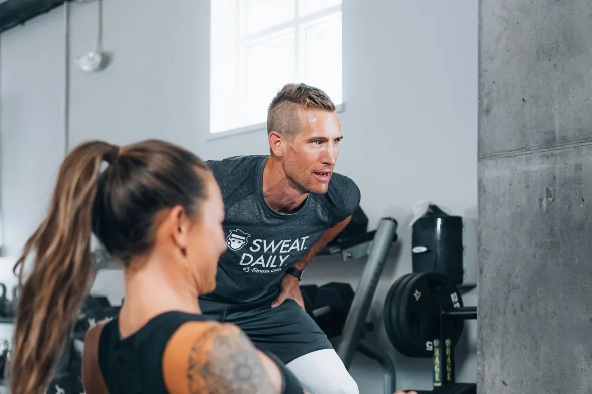 A trainer motivates a clients to keeping pushing through a set.